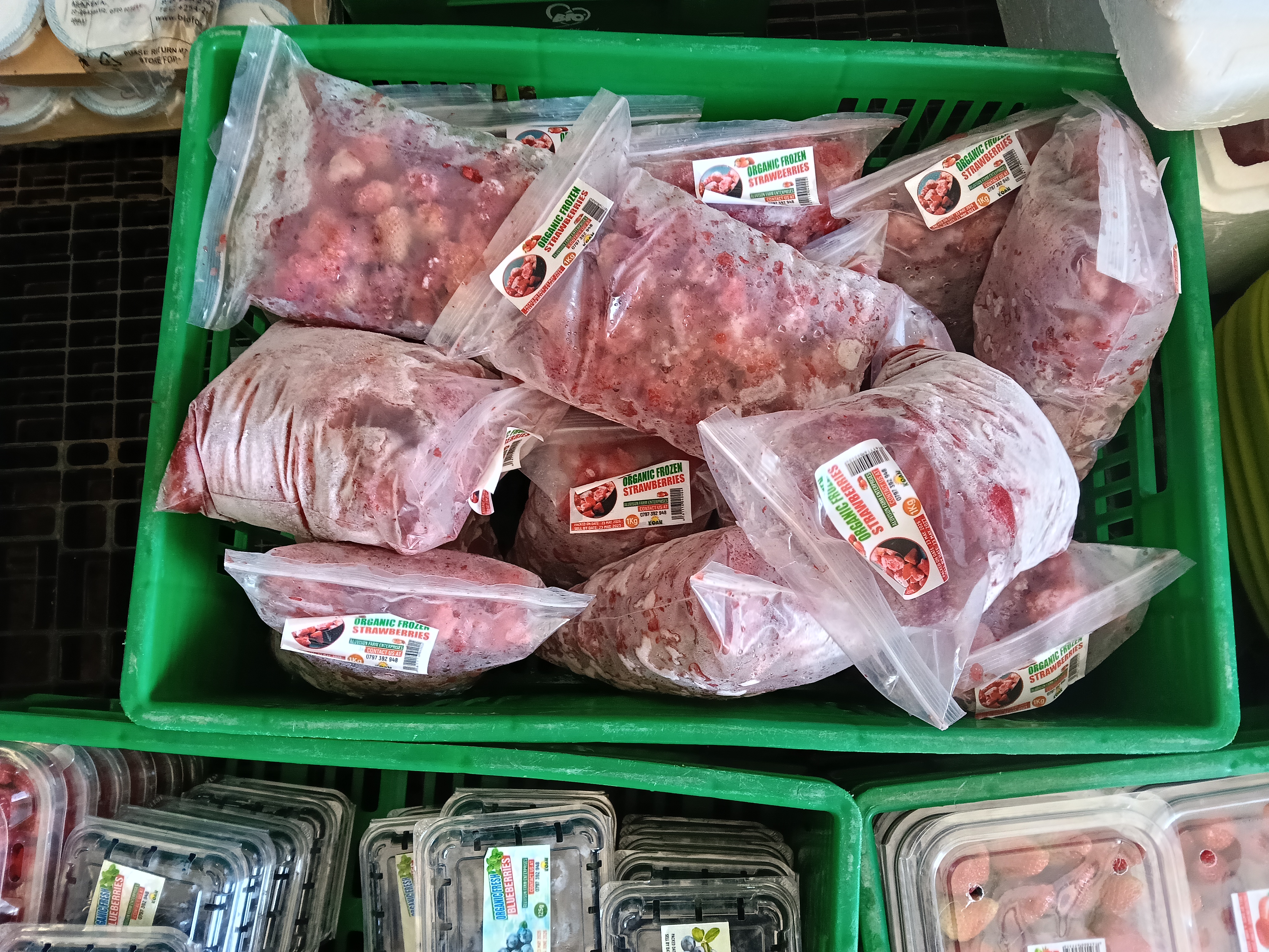 Packs of Aluvison organic frozen strawberries displayed in a produce crate